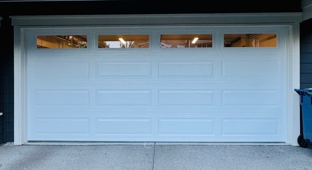 White long raised panel double-car garage door with a row of top windows