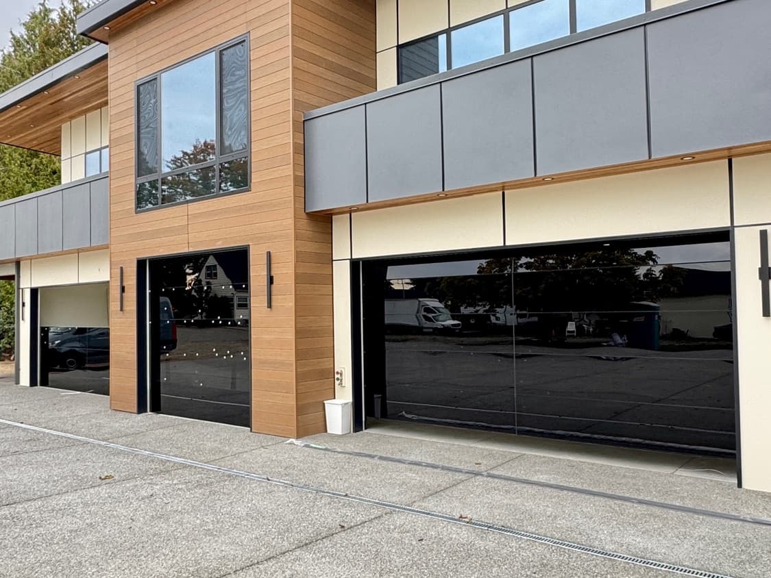 Two full-view aluminum glass garage doors installed on a modern Pacific Northwest home with cedar siding