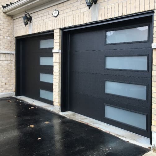 Black flush panel garage doors with offset vertical frosted-glass strip on a brick home