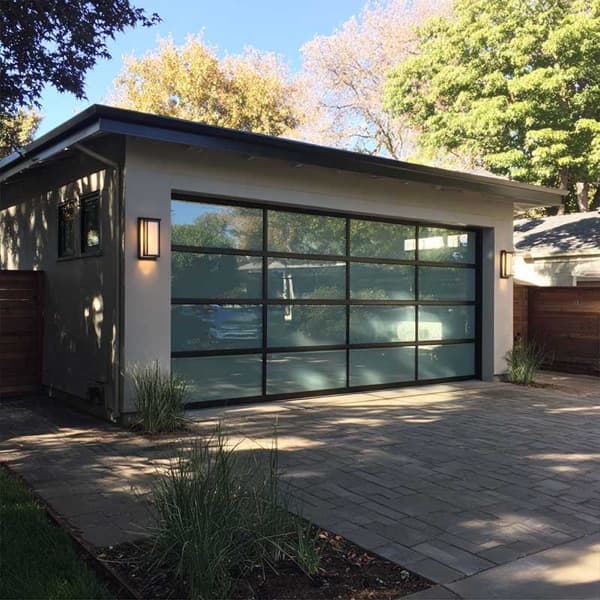 Full-view aluminum garage door with frosted glass panels on a modern mid-century home