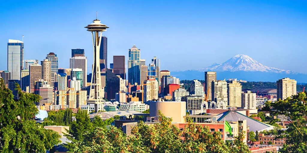 A panoramic view of Seattle’s skyline featuring the Space Needle and Mount Rainier on a clear day.
